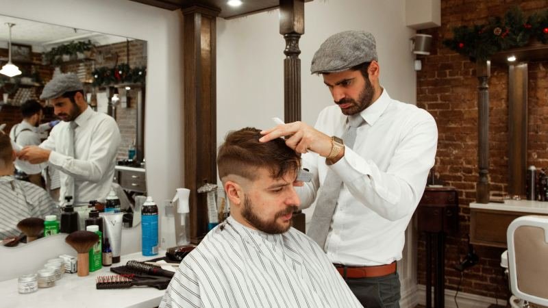 Бръснар преглежда косата на клиент преди подстригване